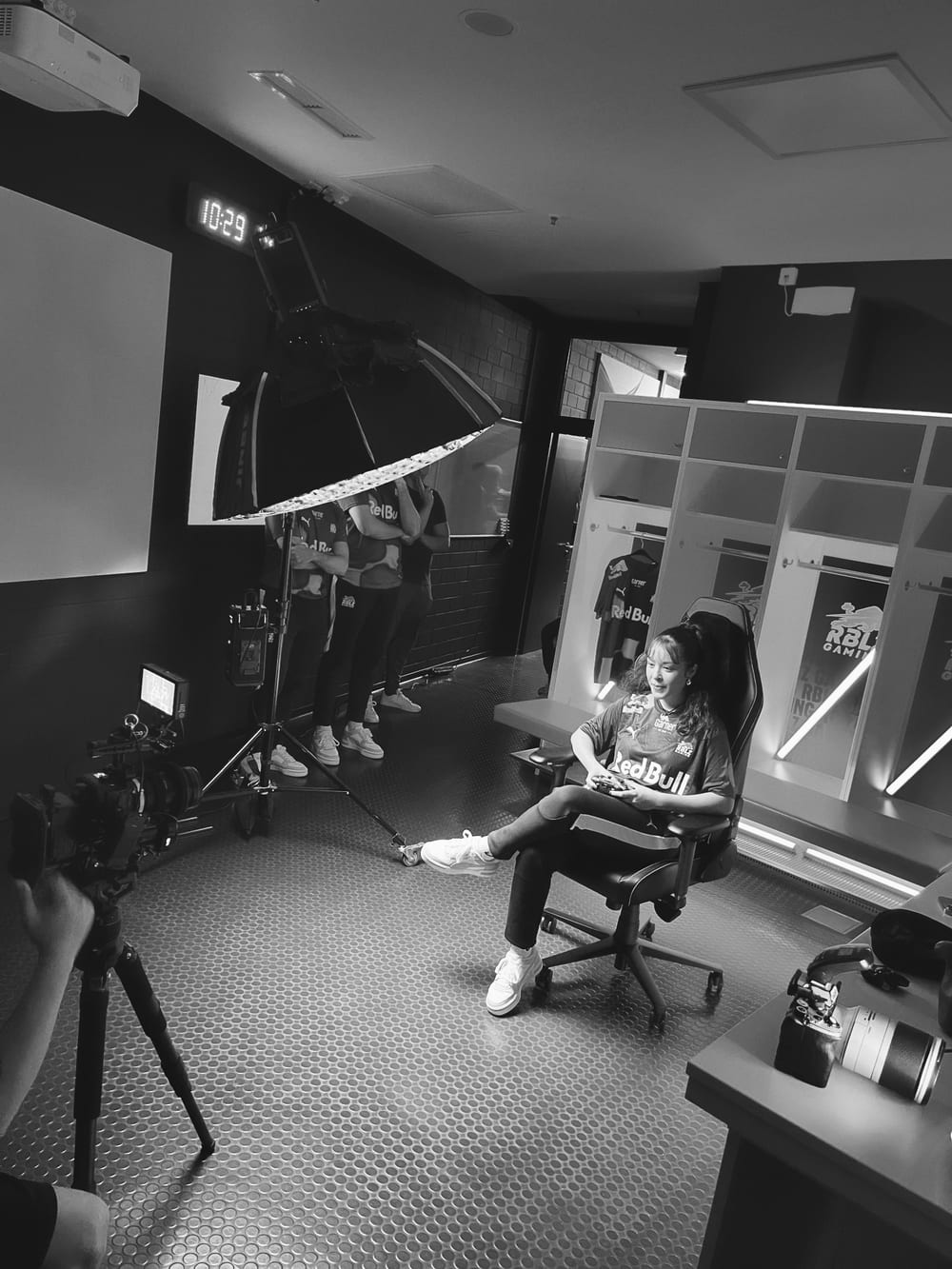 Behind the Scenes in Schwarz-Weiß: Dreh in einer Umkleide mit Kamera, Licht und Spielerin im Gaming-Stuhl