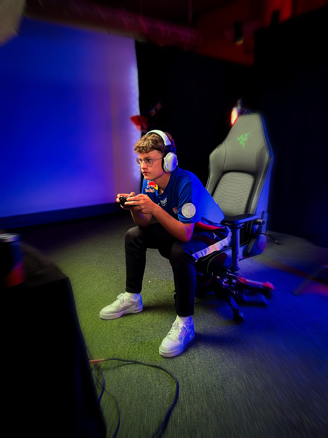 Spieler mit Controller im Gaming-Stuhl unter blauem und rotem Licht