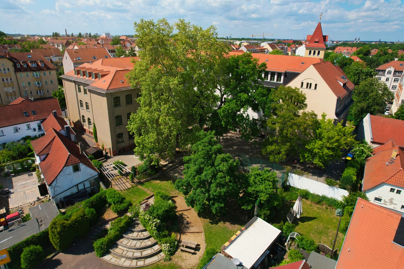 Das Schulgebäude von oben mit Schulhof und Umgebung