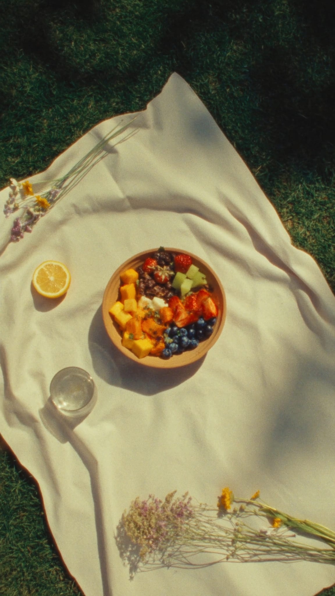Picknickdecke im Gras mit Bowl und Blumen